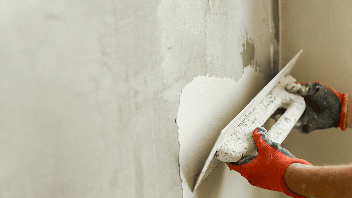 Professional plasterer smoothing wall surface - request a quote